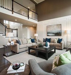 a living room with couches, chairs and a coffee table in front of a staircase