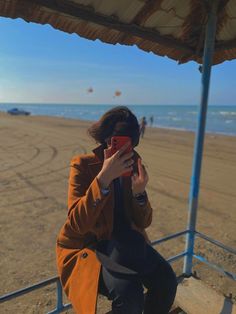 a woman sitting on a bench looking at her cell phone while she takes a photo