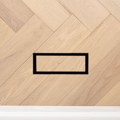 a wooden floor with a black square in the center and a white wall behind it