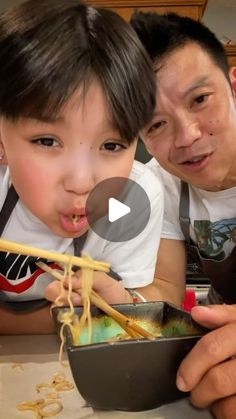 a man and child eating noodles with chopsticks