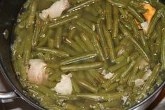 green beans and onions are cooking in a pot on the stove top, with garlic flakes