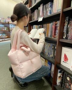 a woman sitting on a chair reading a book in front of a bookshelf