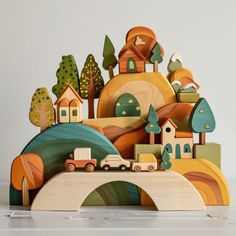 a wooden toy with houses, cars and trees on it's sides is shown in front of a white background