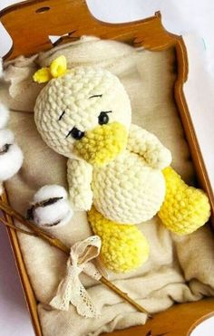 a crocheted stuffed animal is in a wooden box with cotton balls and yarn