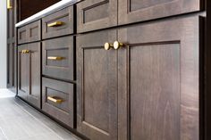 a kitchen with brown cabinets and gold pulls on the doors, along with white tile flooring