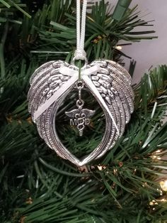 an ornament hanging from a christmas tree with angel wings and the letter m on it