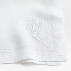 a close up view of a white linen material with embroidered designs on the front and back