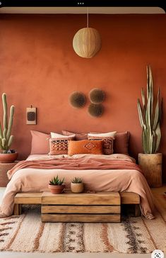 a bedroom with an orange wall and some plants on the bed, along with two potted cacti