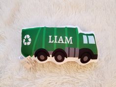 a green garbage truck with the word'i am'on it is laying on a white blanket