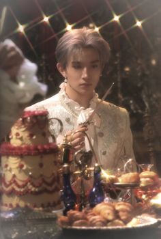 a young man standing in front of a cake with a knife and fork on it