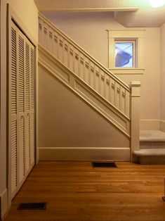 an empty room with wooden floors and stairs