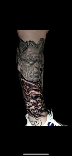 a man's leg with tattoos on it and an image of a demon in the background