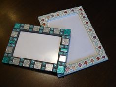 two small mirrors sitting on top of a wooden table next to each other, one with a white and green mosaic design