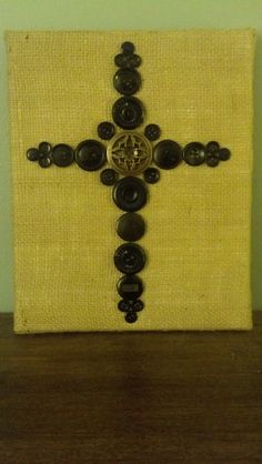 a cross made out of buttons on top of a wooden table