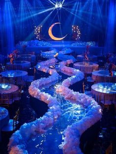 a stage set up for a party with blue lights and white flowers on the floor