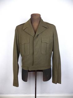 Vintage Eisenhower style, military issued wool jacket. Fully lined in viscose. Button closure hidden under placket. There are also button at waistband to adjust fit. In very good vintage condition for age. No stains, but there are two small holes on the cuff of the right sleeve. Tagged size 40 L. Actual measurements below. Length 20", shoulders 17", sleeves 25", chest 42", waistband 36"-37" Please note that vintage clothing and contemporary sizes can vary greatly. We take measurements of listed garments by laying the garment flat and then doubling the measurement. When considering whether a garment would fit, we suggest taking a similar garment from your own wardrobe and measure it lying flat as we do. Then compare the measurements. Military Style Wool Outerwear In Khaki, Military Style Khaki Blazer Single Breasted, Military Style Khaki Blazer With Flap Pockets, Khaki Military Style Single Breasted Blazer, Vintage Khaki Blazer With Lapel Collar, Vintage Single-breasted Khaki Blazer, Khaki Military Blazer With Flap Pockets, Vintage Khaki Single-breasted Blazer, Vintage Outerwear With Epaulettes For Fall