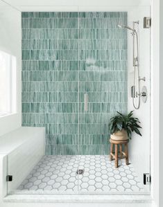 a green tiled bathroom with a stool and shower