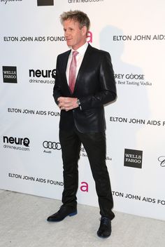 a man in a suit and tie standing on the red carpet at an awards event