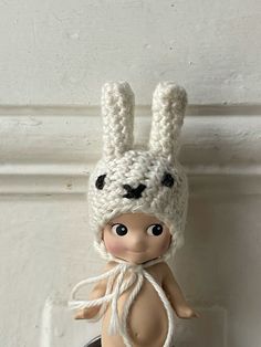 a small doll wearing a knitted bunny hat