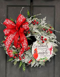 a red and white christmas wreath with cardinal's, snowflakes, and an angel ornament