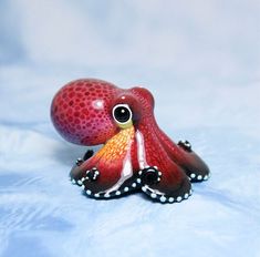 an octopus figurine sitting on top of a white sheet with black dots around it's eyes