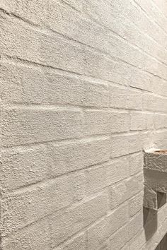 the corner of a white brick wall next to a toilet