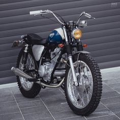 a motorcycle parked in front of a garage door next to a brick floored area