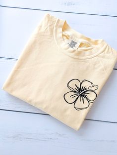 Hibiscus Flower TShirt | Comfort Colors Flower Shirt | Floral Tee ✳ The photo sample shows a butter tee ✳ SIZING - Please review the size chart to select the best fit. All sweatshirts are unisex. ✳ FEATURES ring spun cotton, garment-dyed - These colors provide a vintage look that will remain for the life of the garment. relaxed fit - For those who want the right feel without all the clinginess. double-needle topstitched collar twill taped neck and shoulders for extra durability double-needle arm White Hibiscus Print T-shirt For Spring, White Cotton Top With Hibiscus Print, White Cotton Hibiscus Print Shirt, White Cotton Shirt With Hibiscus Print, White Hibiscus Print Graphic Tee, White Graphic Tee With Hibiscus Print, Spring Hibiscus Print Short Sleeve T-shirt, White T-shirt With Hibiscus Print For Spring, White Hibiscus Print Crew Neck T-shirt