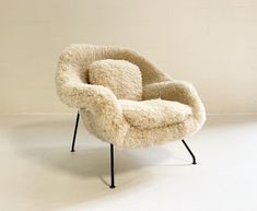 the chair is made out of sheepskin and has black metal legs, with a white background