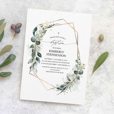 a wedding card with eucalyptus leaves and greenery on the front, surrounded by foliage