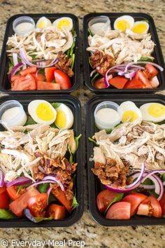 four plastic trays filled with food on top of a marble countertop next to each other