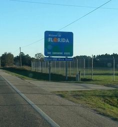 a sign on the side of a road that says welcome to florida in front of an empty field