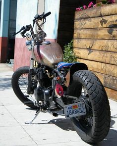 the motorcycle is parked on the side of the road near a building with flowers in it