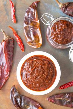 chili paste in a white bowl surrounded by red peppers