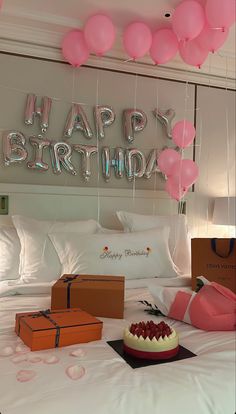 a birthday cake and balloons on a bed