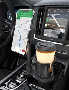 a car dashboard with a cup holder holding a phone and a coffee mug in it