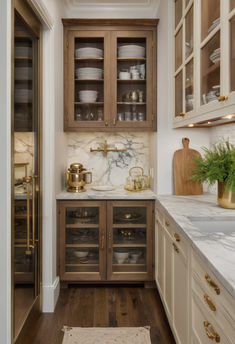 a kitchen with wooden cabinets and marble counter tops, gold accents on the upper cabinet doors