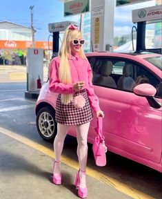 a woman in pink is standing next to a pink car and holding a pink purse