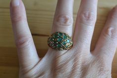 This ring is gold plated over sterling silver and is set with numerous small emeralds in a domed style setting. The stones are lower commercial quality emeralds and are somewhat opaque but still have nice green color. Condition is good with general light wear from age and light tarnish, if polished the ring would have a bright gold finish.  Item is sold as-is. We welcome haggling in this shop! Unique Green Emerald 14k Gold Ring, Vintage Hallmarked Emerald Jewelry, Unique Green Emerald Ring In 14k Gold, Unique 14k Gold Green Emerald Ring, Unique 14k Gold Emerald Ring, Antique Gold Rings With Emerald, Antique Emerald Ring Jewelry, Gold Emerald Ring Hallmarked, Gold Emerald Ring Jewelry