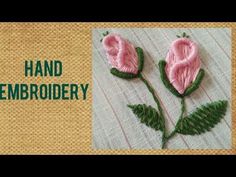 two pink flowers with green leaves are on a white cloth and the words hand embroidery