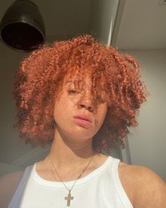 a close up of a person with red hair and a cross pendant on her necklace