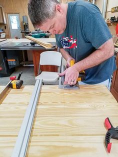 a man working on a piece of plywood in his workshop with a planer