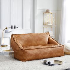 a living room with a brown leather couch and white rugs on the floor next to a lamp