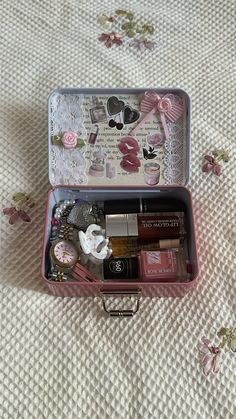 an open pink suitcase on a bed with flowers and laces around the edges, containing various items