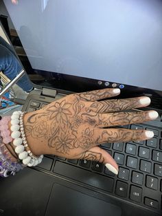 a woman's hand on top of a laptop keyboard with tattoos on her arm