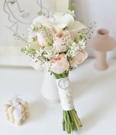 a bouquet of flowers sitting on top of a white table next to a small vase