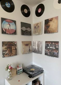 there are many records hanging on the wall next to a table with a record player