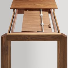 a wooden table with an open drawer on it's top and two keys attached to the lid