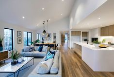 a living room filled with furniture next to a kitchen and dining room table on top of a hard wood floor