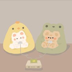 two small stuffed animals sitting next to each other on a table with an electronic device in front of them